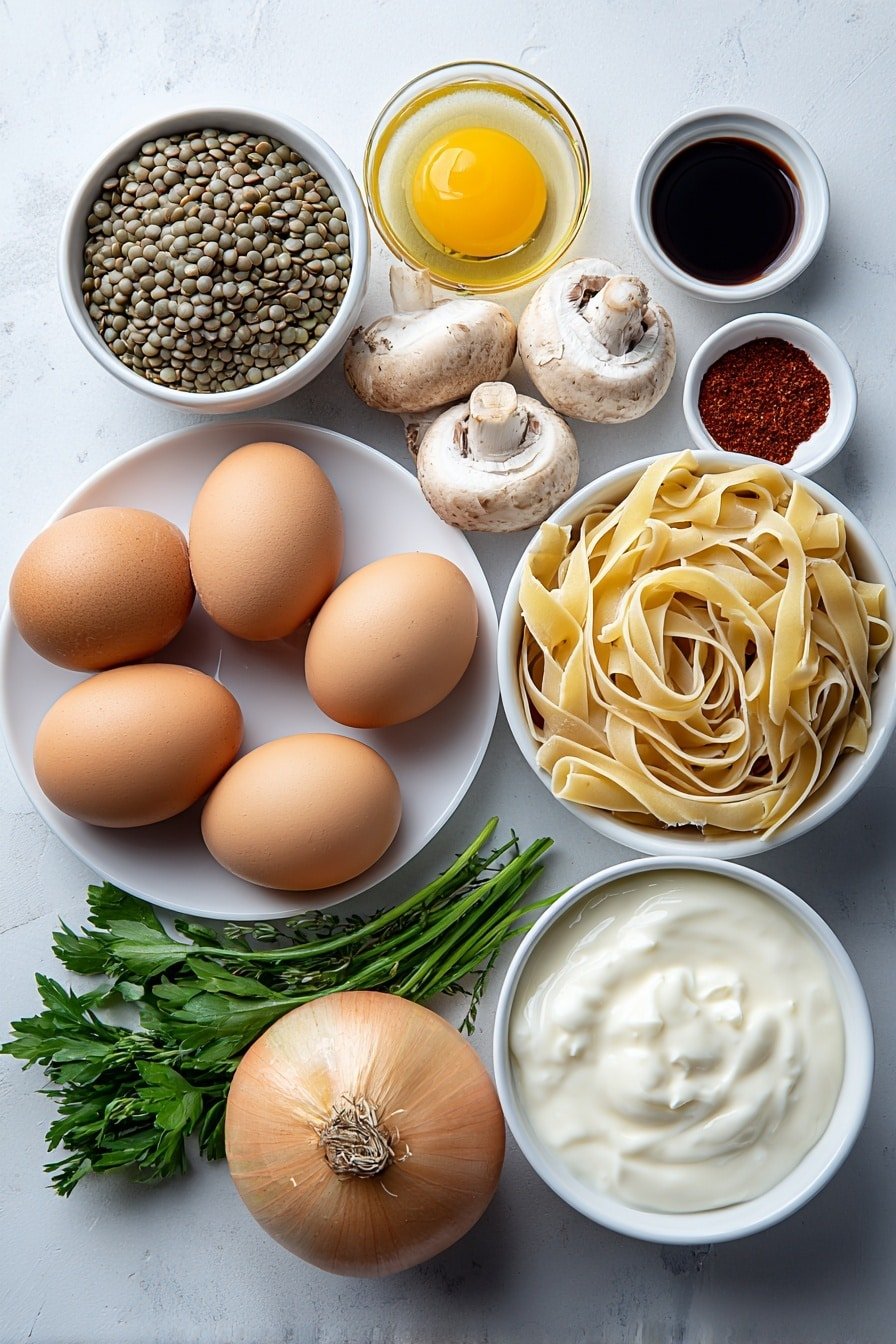 Flat lay of dry green lentils in a small pile, whole uncracked brown eggs, a neatly coiled nest of fettuccine pasta, a small white bowl of golden olive oil, a whole yellow onion with papery skin, three whole garlic cloves, sliced cremini mushrooms arranged in a fan shape, a small white bowl of dark soy sauce, a small white bowl of smoked paprika powder, a small white bowl of dried thyme leaves, a small white bowl filled with light vegetable broth, a small white bowl of creamy unsweetened plant-based yogurt, a small bunch of fresh green parsley sprigs placed symmetrically, all on simple white ceramic plates and bowls, placed on a clean white marble surface, soft natural light, photo taken with an iPhone, professional food photography style, fresh ingredients, white ceramic bowls, no bottles, no duplicates, no utensils, no packaging --ar 2:3 --v 7 --p m7354639359234015250 — Lentil Mushroom Stroganoff, vegan mushroom stroganoff, hearty vegetarian stroganoff, creamy lentil mushroom sauce, comforting mushroom and lentil dish