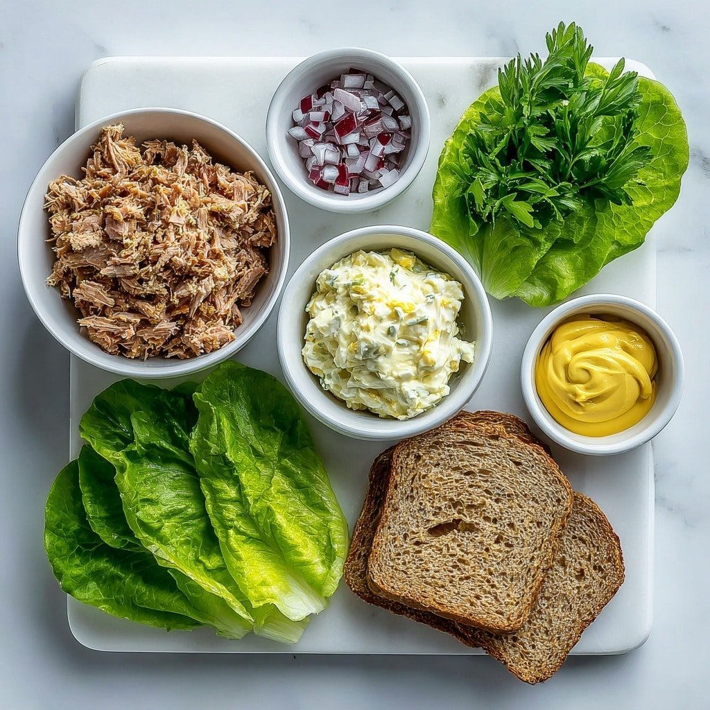 Flat lay of a small white ceramic bowl filled with flaky, moist tuna, a small white bowl with creamy mayonnaise, a few crisp celery stalks with bright green leaves, finely diced small pile of red onion, a small white bowl holding smooth Dijon mustard, two fresh crisp green lettuce leaves, and two slices of seeded whole grain bread arranged neatly, all placed on a clean white marble surface, soft natural light, photo taken with an iPhone, professional food photography style, fresh ingredients, white ceramic bowls, no bottles, no duplicates, no utensils, no packaging --ar 1:1 --v 7 --p m7354639359234015250 — Tuna Salad Sandwich, classic tuna salad sandwich, tuna sandwich ideas, easy tuna salad recipe, best tuna salad sandwich