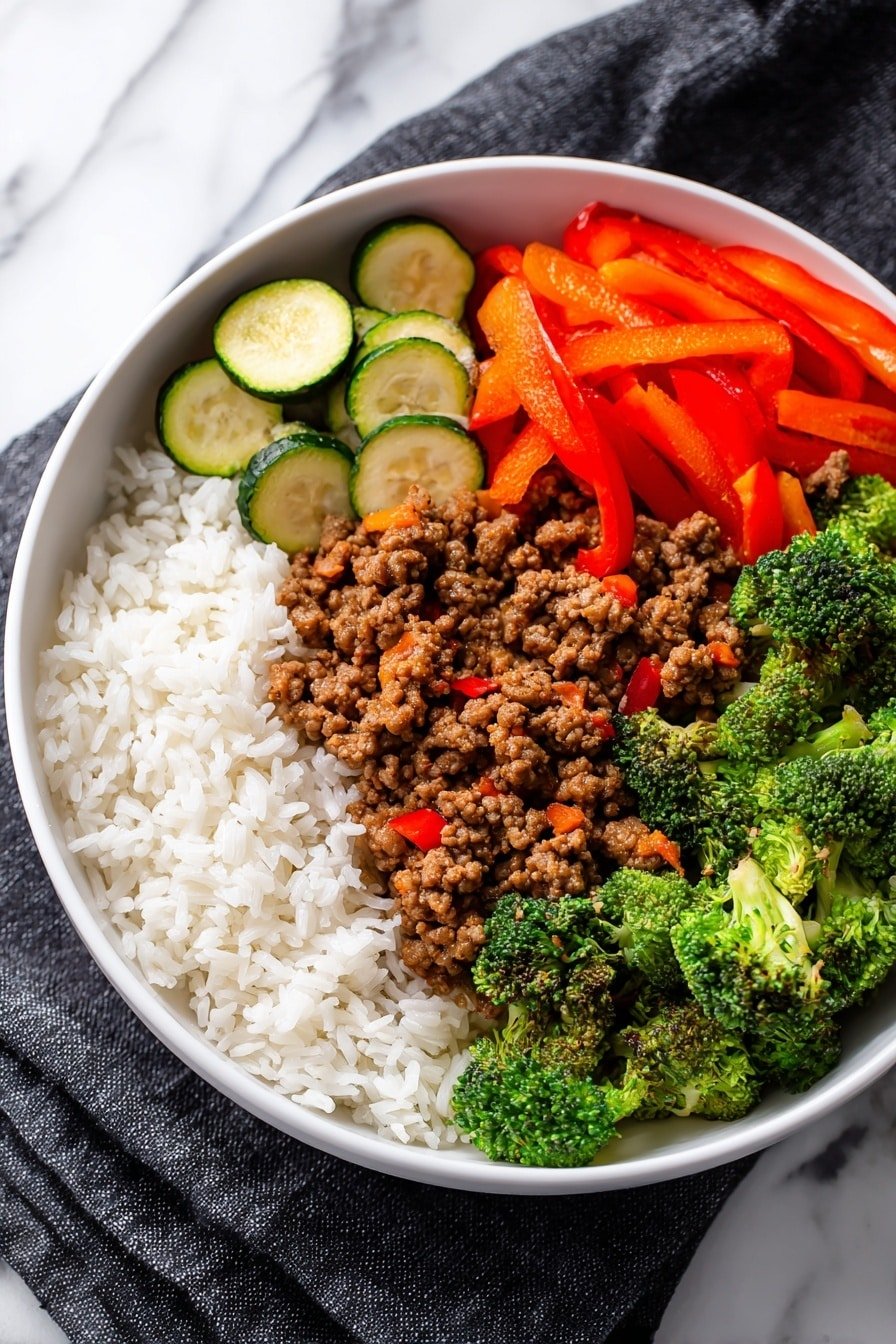 A white bowl filled with four distinct sections: the top left has a layer of fluffy white rice with visible individual grains, the bottom left shows several slices of cooked zucchini with light grill marks and a soft green shade, the center is filled with brown cooked ground meat mixed with small pieces of orange carrot and red pepper, and the right side features steamed broccoli florets with a rich green color and bright orange and red bell pepper strips layered above, all sitting on a dark cloth with a white marbled surface underneath, photo taken with an iphone --ar 2:3 --v 7 — Spicy Ground Beef Stir-Fry with Veggies, spicy beef stir-fry recipe, quick weeknight beef stir-fry, healthy veggie beef stir-fry, easy spicy beef dinner