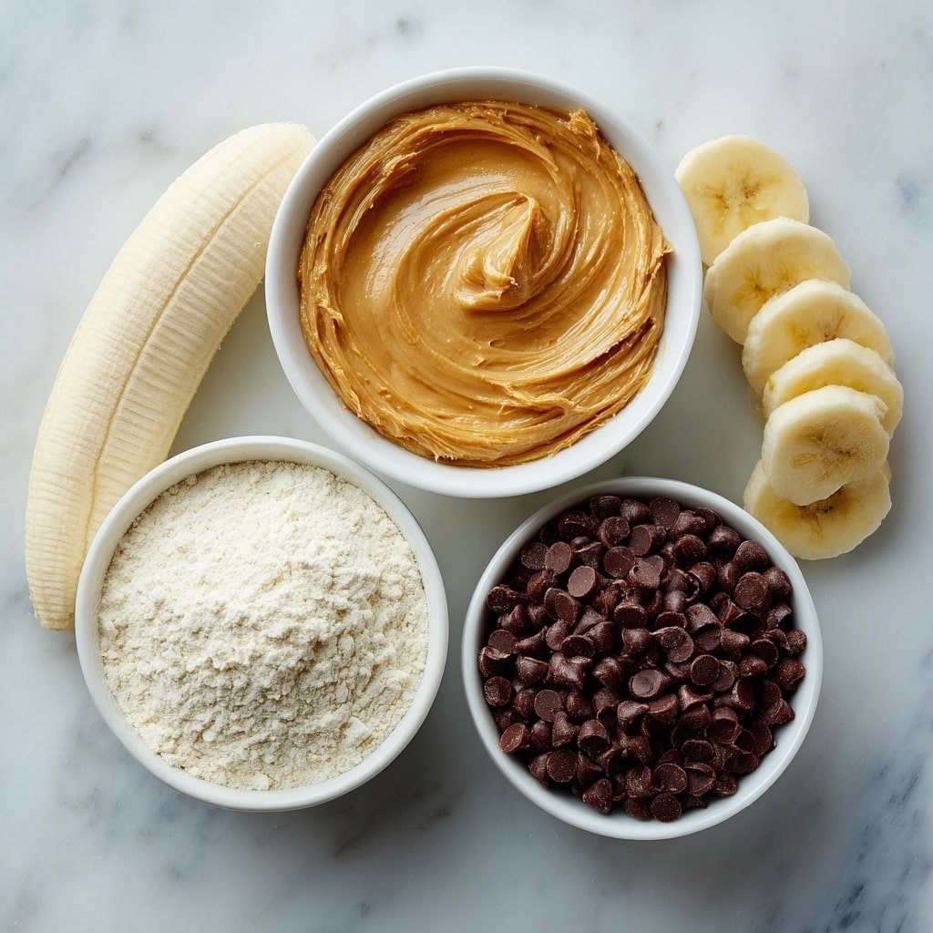 Flat lay of a small white ceramic bowl filled with smooth, runny peanut butter, a peeled ripe banana sliced lengthwise showing its creamy texture, a small white ceramic bowl containing fine vanilla protein powder, and a small white ceramic bowl holding glossy dark chocolate chips, all arranged in perfect symmetry, placed on a clean white marble surface, soft natural light, photo taken with an iPhone, professional food photography style, fresh ingredients, white ceramic bowls, no bottles, no duplicates, no utensils, no packaging --ar 1:1 --v 7 --p m7354639359234015250 — Peanut Butter Banana Cookie Dough Fudge Cups, peanut butter banana dessert, no-bake fudge cups, banana and peanut butter treats, easy cookie dough fudge